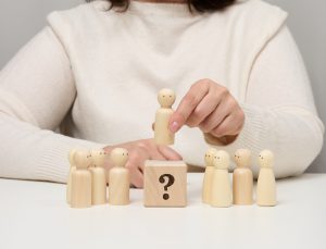 Woman keeps the red wooden figurine separate from the group. Career growth concept, unique person.