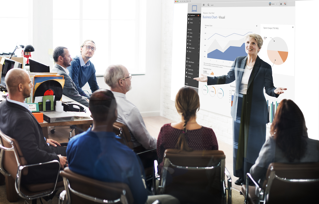 Mature business woman presenting data and figures to corporate group